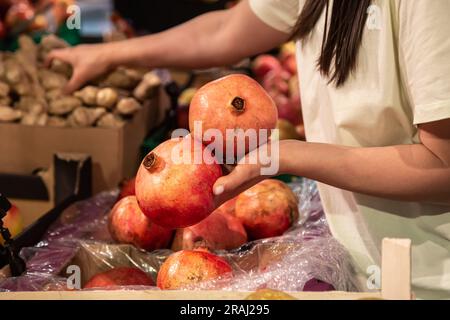 The woman holds pomegranate in the store or in the market, close up. Stock Photo