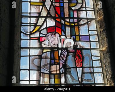 light shining through new coloured stained glass window depicting St Cuthbert with crook in Lindisfarne Priory, Holy Island, Northumbria, England, UK Stock Photo