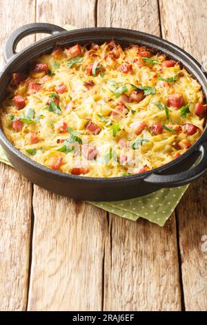 German potato pancake Dibbelabbes with bacon and leek close-up in a frying pan on the table. Vertical Stock Photo