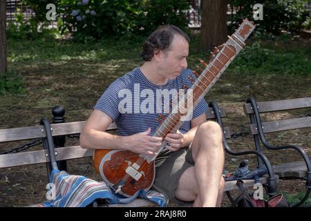 A Man playing the sitar in Washington Square Park in Greenwich Village, Manhattan, New York City, Summer 2023. Stock Photo