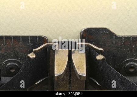 Close up of a vintage 1910s manual typewriter's type guide and ribbon with yellow paper on platen providing copy space Stock Photo