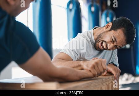 Strength, motivation and men arm wrestling in a gym on a table while being playful for challenge. Rivalry, game and male people or athletes doing Stock Photo