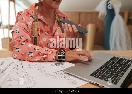 Tailor checking e-mails from clients and recording voice messages Stock Photo