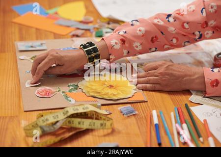 Hands of creative woman making collage with cut photos of flowers Stock Photo