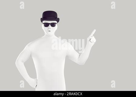 Disguised man dressed in white bodysuit pointing to side with forefinger Stock Photo