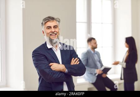 Confident mature businessman leader standing with arms folded Stock Photo