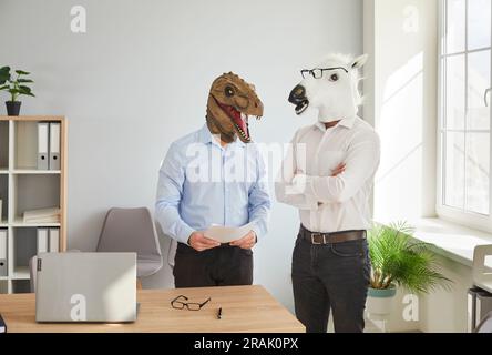 Two funny business men wearing animal masks standing in office and having discussion. Stock Photo