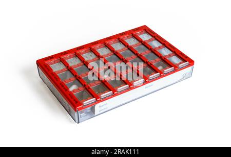 A red plastic 28-slot dosette box, or medical pill dispenser, isolated on a white background, UK Stock Photo