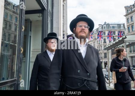 London- June 2023:London- June 2023: Shoppers on Jewish traditional dress on Regent Street- landmark shopping destination Stock Photo