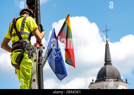 Installing surveillance and security cameras with flags of NATO and of Lithuania before Nato summit 2023 in the centre of Vilnius with tower bell Stock Photo