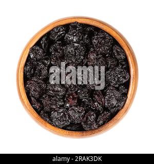 Dried sour cherries, pitted tart or dwarf cherries, in a wooden bowl. Dark-red cultivar Morello cherry, small fruits of Prunus cerasus. Stock Photo