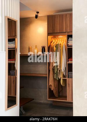 Wardrobe with clothes and mirror in stylish dressing room Stock Photo