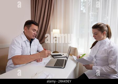 Two doctors man and woman talking, looking at computer screen Stock Photo