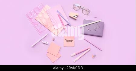 Sticky note with word DONE, eyeglasses and stationery on lilac background Stock Photo