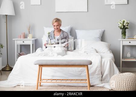 Mature woman having breakfast in bed Stock Photo