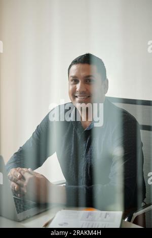 Portrait of cheerful businessman working with documents at office table Stock Photo