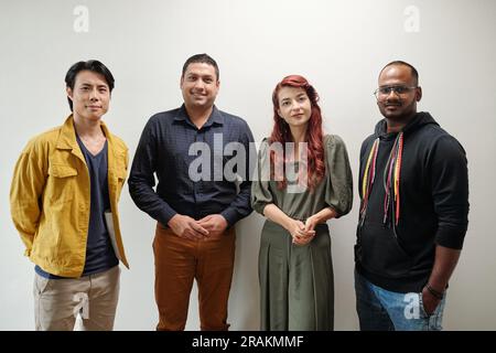 Portrait of diverse team of software developers standing against office wall Stock Photo