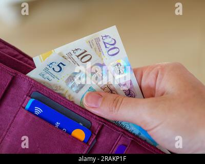 Close up of hand taking pound notes in cash out of wallet Stock Photo