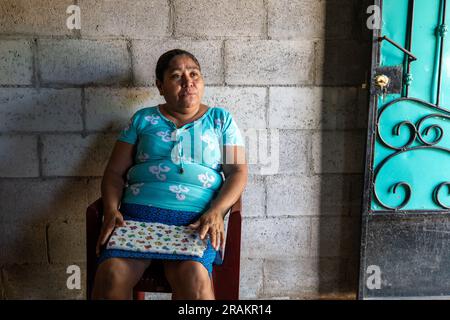 Ahuachapán, El Salvador - November 04 2022: Salvadoran Woman Dressed in Aqua Sits on a Chair Outside her Home Stock Photo