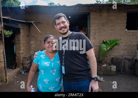 Ahuachapán, El Salvador - November 04 2022: Salvadoran Woman Hugging a Tall Man Outside her Adobe Home Stock Photo