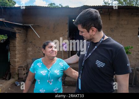 Ahuachapán, El Salvador - November 04 2022: Salvadoran Woman Hugging a Tall Man Outside her Adobe Home Stock Photo