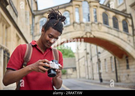 Young Man Travelling On Vacation Taking Photo With Camera When Sightseeing In Oxford Stock Photo