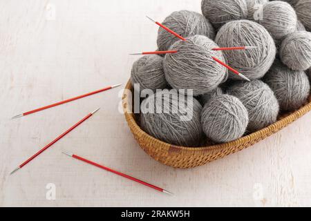 Double pointed knitting needles and balls of yarn in basket Stock Photo