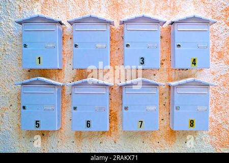 Eight letter boxes on a wall, waiting for a snail mail love letter. Stock Photo