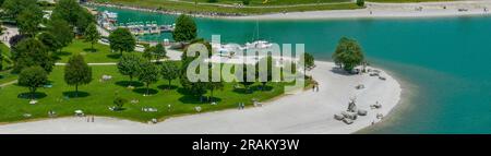 Aerial view of Lake Molveno, park and green area. Lake beach. People relaxing and sunbathing, moored boats. 06-29-2023. Trentino, Brenta Dolomites. Stock Photo