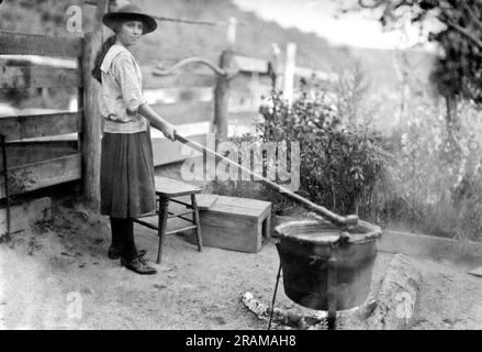 Little Orleans, Maryland:  October 28, 1920. A young girl making apple butter the same way her great great grandparents made it years ago. She is using the same iron pot and stirring stick that has been used for years. it is easy to make, and only requires five hours of constant stirring. Stock Photo