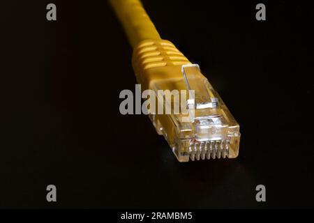 Macro photo of a yellow 8 pin ethernet plug on black background Stock Photo