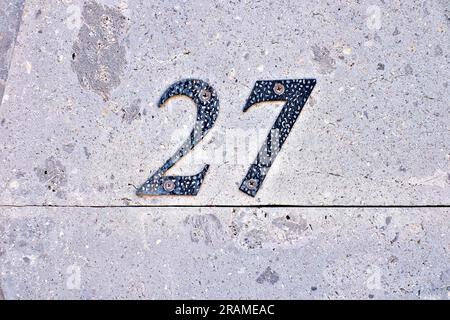 Number 27, twenty-seven, metal number on stone background. Stock Photo