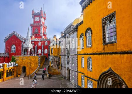 The brightly colored clocktower in the convent section with the Courtyard of Arches and private chapel of the Pena Palace or Palácio da Pena historic palace castle in Sintra, Portugal. The fairytale castle palace is considered one of the finest examples of 19th century Portuguese Romanticism architecture in the world. Stock Photo