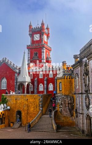 The brightly colored clocktower in the convent section with the Courtyard of Arches and private chapel of the Pena Palace or Palácio da Pena historic palace castle in Sintra, Portugal. The fairytale castle palace is considered one of the finest examples of 19th century Portuguese Romanticism architecture in the world. Stock Photo