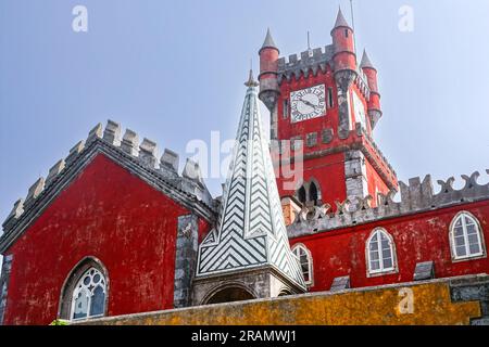 The brightly colored clocktower in the convent section seen from the Courtyard of Arches and private chapel of the Pena Palace or Palácio da Pena historic palace castle in Sintra, Portugal. The fairytale castle palace is considered one of the finest examples of 19th century Portuguese Romanticism architecture in the world. Stock Photo