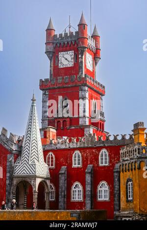 The brightly colored clocktower in the convent section seen from the Courtyard of Arches and private chapel of the Pena Palace or Palácio da Pena historic palace castle in Sintra, Portugal. The fairytale castle palace is considered one of the finest examples of 19th century Portuguese Romanticism architecture in the world. Stock Photo