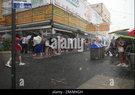 New York, USA. 04th July, 2023. People take cover at Nathan's Famous hot dog restaurant along Surf Avenue during heavy rains at Coney Island, in the Brooklyn borough of New York, NY, July 4, 2023. The thunderstorm caused part of Nathan's Famous Fourth of July Hot Dog Eating Contest to be postponed. (Photo by Anthony Behar/Sipa USA) Credit: Sipa USA/Alamy Live News Stock Photo