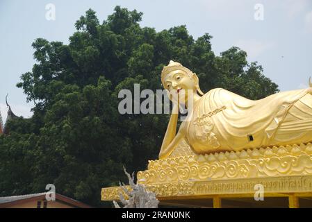 The outdoor Reclining golden Buddha image at Wat Mai Supaditharam temple for Buddhists Worship for travel to pay homage to the holy things. Stock Photo