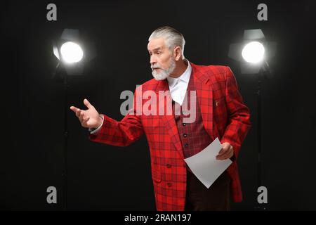 Senior actor with script performing on stage Stock Photo