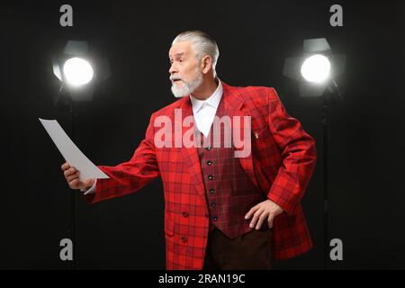 Senior actor with script performing on stage Stock Photo