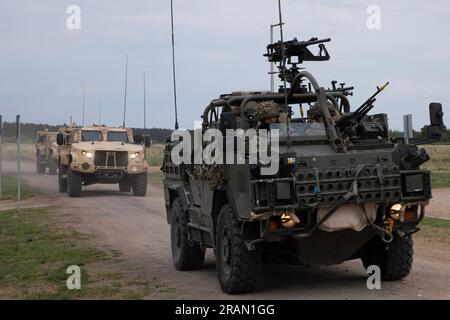 U.S. Soldiers with Headquarters and Headquarters Company, 1st Battalion, 9th Cavalry Regiment, 2nd Armored Brigade Combat Team, 1st Cavalry Division, supporting the 4th Infantry Division, along with British army soldiers with the U.K. Royal Lancers, Aliwal Troop, supporting NATO’s enhanced Forward Presence Battle Group Poland, return from operation Aliwal Surge at Bemowo Piskie Training Area, Poland, July 3. Aliwal Surge was a short-notice readiness exercise designed to test the interoperability and innovation of the participating military units including American elements supporting the 4th I Stock Photo