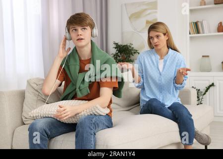 Teenage son listening music in headphones or playing online games ignoring  his mother Stock Photo - Alamy