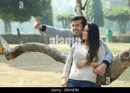 Beautiful Indian happy college students looking into the mobile phone in a day time. They are having a happy moment and enjoying pleasant weather. Stock Photo