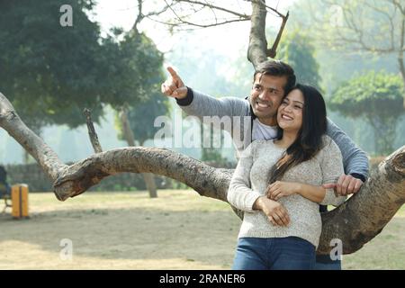 Beautiful Indian happy college students looking into the mobile phone in a day time. They are having a happy moment and enjoying pleasant weather. Stock Photo