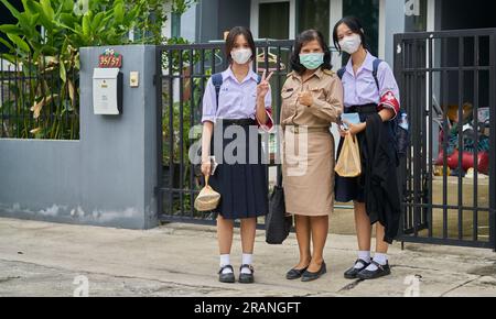 a Thai teacher and her daughters all dressed in their school uniforms. Stock Photo