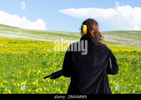 Woman with gun in field Stock Photo