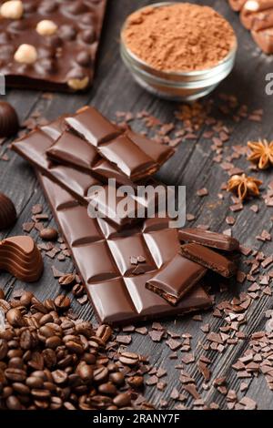 Chocolate, cocoa powder, chocolate chips, cinnamon, star anise on a dark wooden background. Handmade chocolate with nuts and spices. Stock Photo