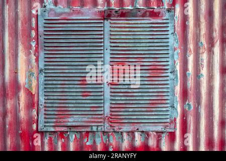 The vent in the wall of a red corrugated metal building Stock Photo