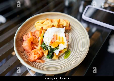 Potato waffles, Poached egg, avocado cream with salmon and egg . Healthy breakfast, protein. Restaurant dish.  Stock Photo