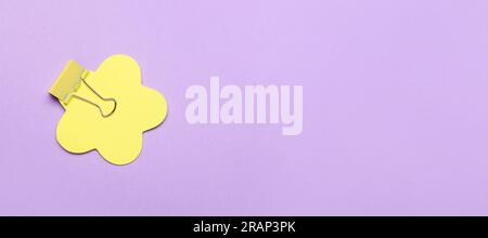 Yellow sticky note with binder clip on lilac background with space for text Stock Photo